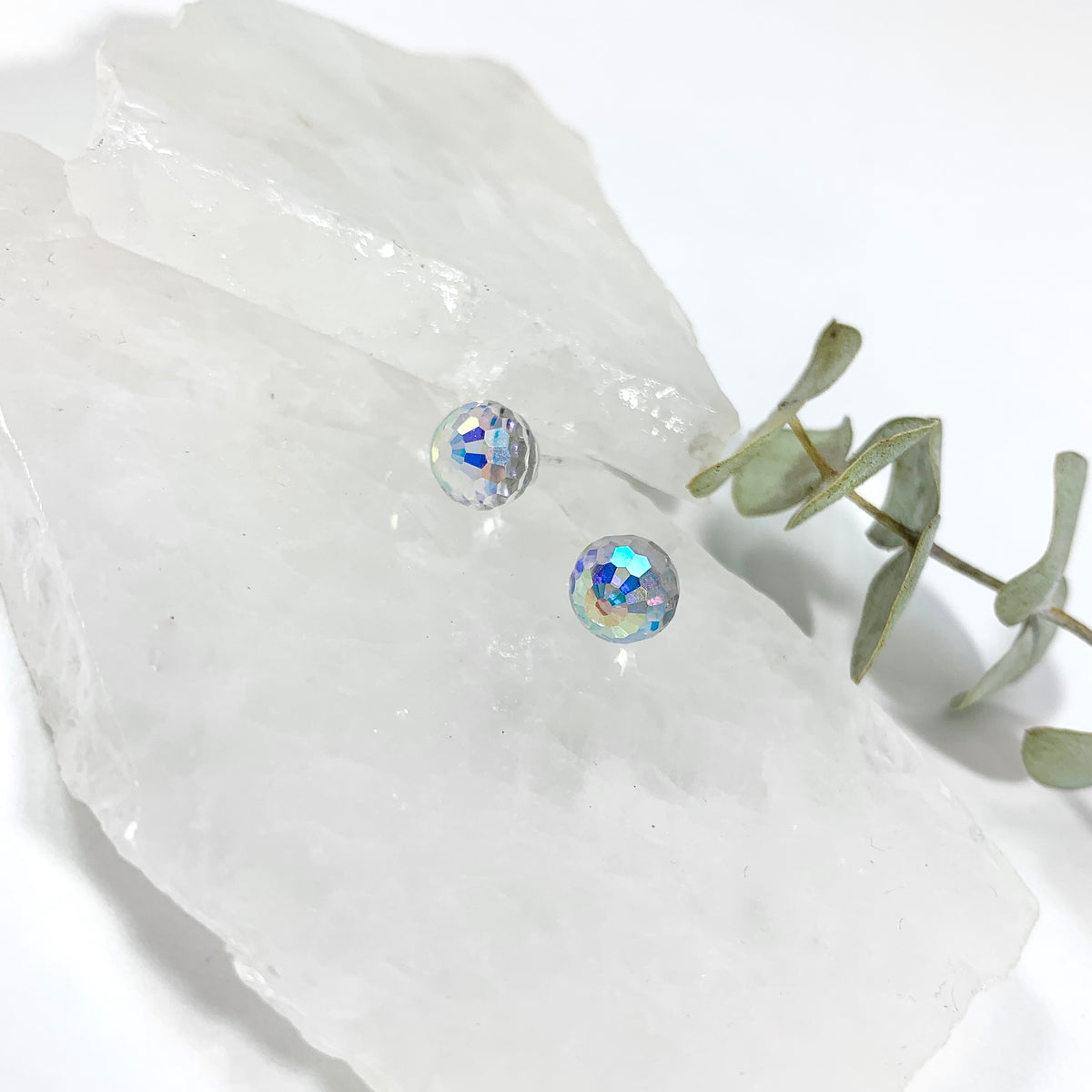 Aurora Borealis disco stud earrings with 8mm faceted Austrian crystal showing rainbow iridescent sparkle on raw white crystal with eucalyptus, sparkly stud earrings for sensitive ears by Blue Jeans and Pearls Saskatchewan