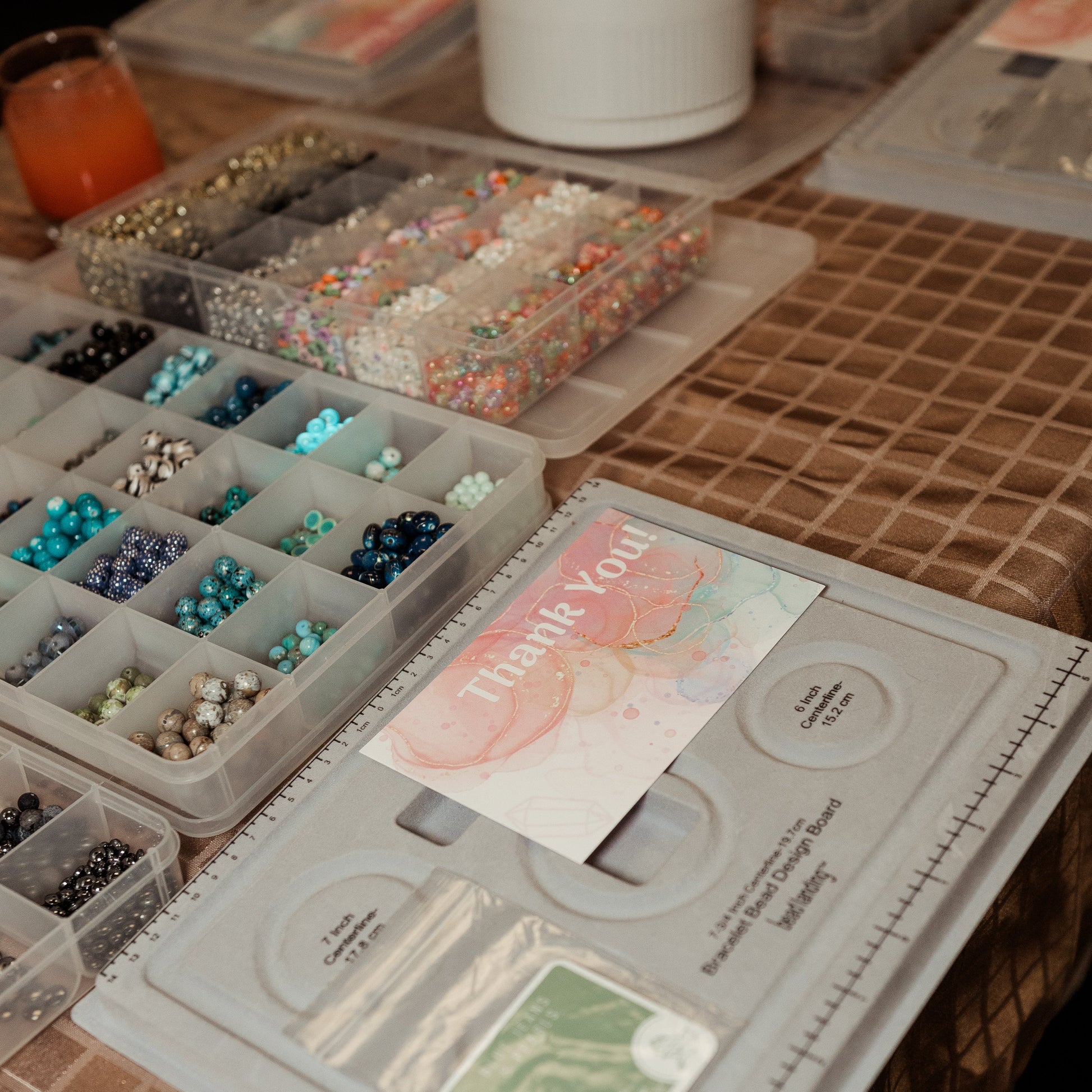 Jewelry-making supplies on a table with a 'Thank You' card.