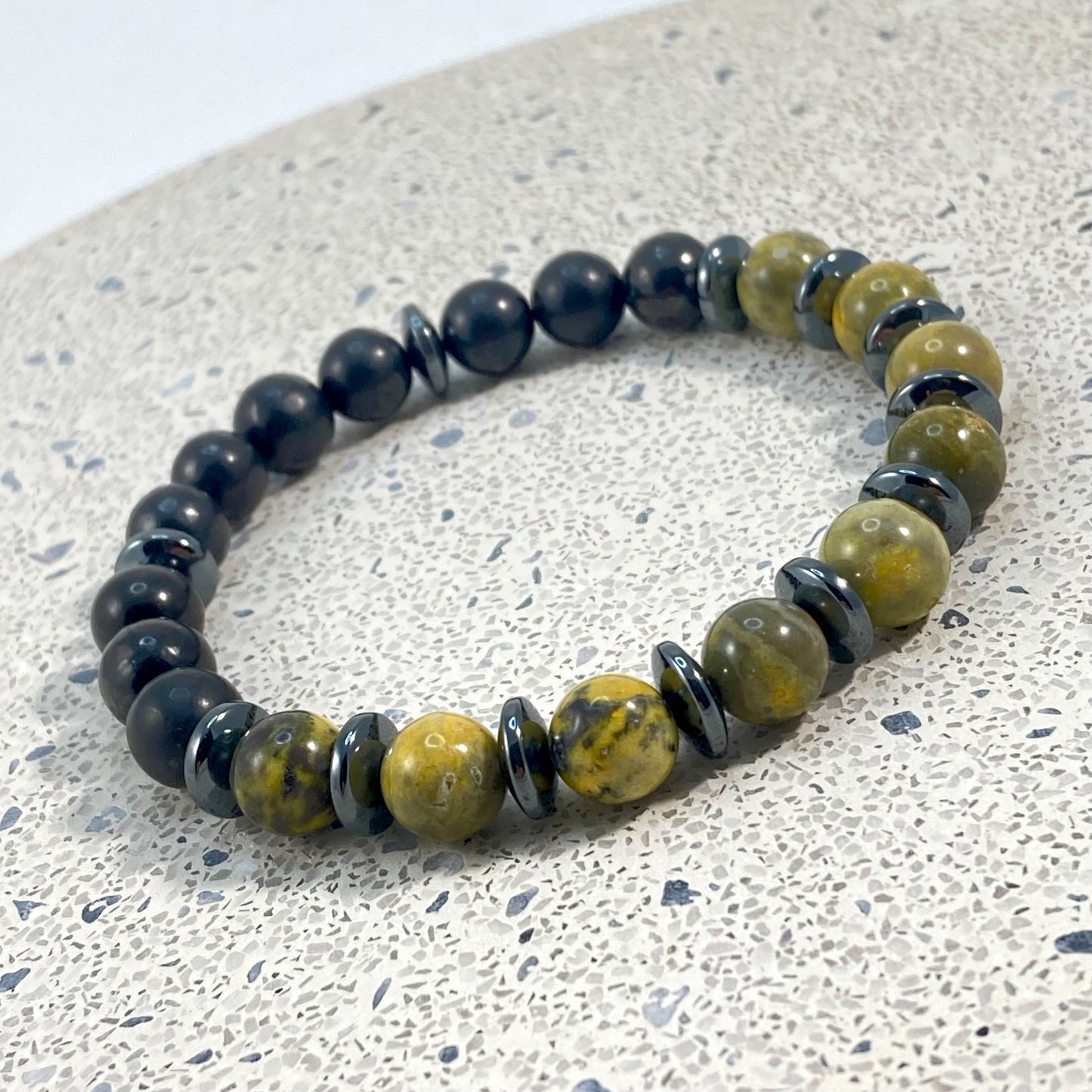 Men's Bumblebee Jasper, Shungite and Hematite handmade bracelet with matte black shungite beads, yellow bumblebee jasper and hematite saucer spacers on terrazzo, grounding men's gemstone jewelry handcrafted by Blue Jeans and Pearls Saskatchewan