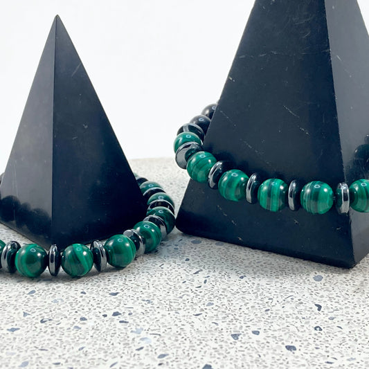 Men's Malachite, Shungite and Hematite handmade bracelets with banded green malachite 8mm beads and hematite spacers draped on black pyramids on terrazzo, protective men's gemstone jewelry by Blue Jeans and Pearls Saskatchewan