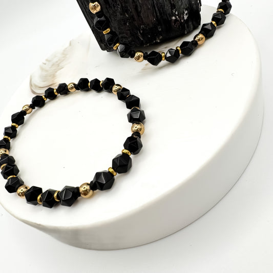 Quiet Power handmade starcut black onyx and gold hematite bracelet displayed on white ceramic pedestal with raw black tourmaline, grounding protection jewelry by Blue Jeans and Pearls Saskatchewan