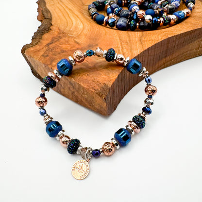 Silver Horizon handmade electroplated hematite and Czech glass bracelet with rose gold charm displayed on natural wood slab alongside Living Skies bracelet, stackable handmade jewelry by Blue Jeans and Pearls Saskatchewan