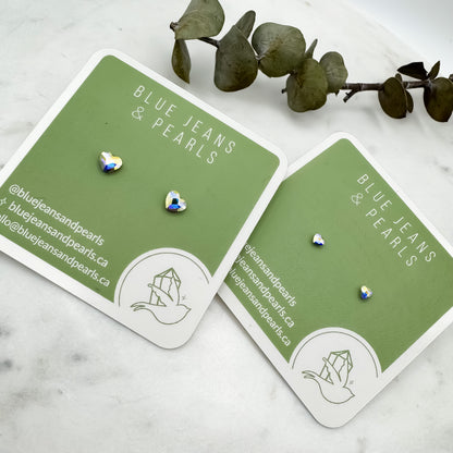 Small Heart Stud earrings in aurora borealis Austrian crystal shown in two sizes on sage green Blue Jeans and Pearls cards with eucalyptus on marble, metal-free studs for sensitive ears by Blue Jeans and Pearls Saskatchewan