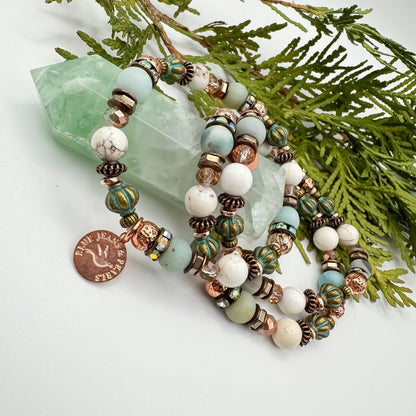 Soft Horizons handmade amazonite, howlite and teal Czech glass bracelet stack draped on green fluorite crystal point with cedar, unique intentional gemstone jewelry by Blue Jeans and Pearls Saskatchewan