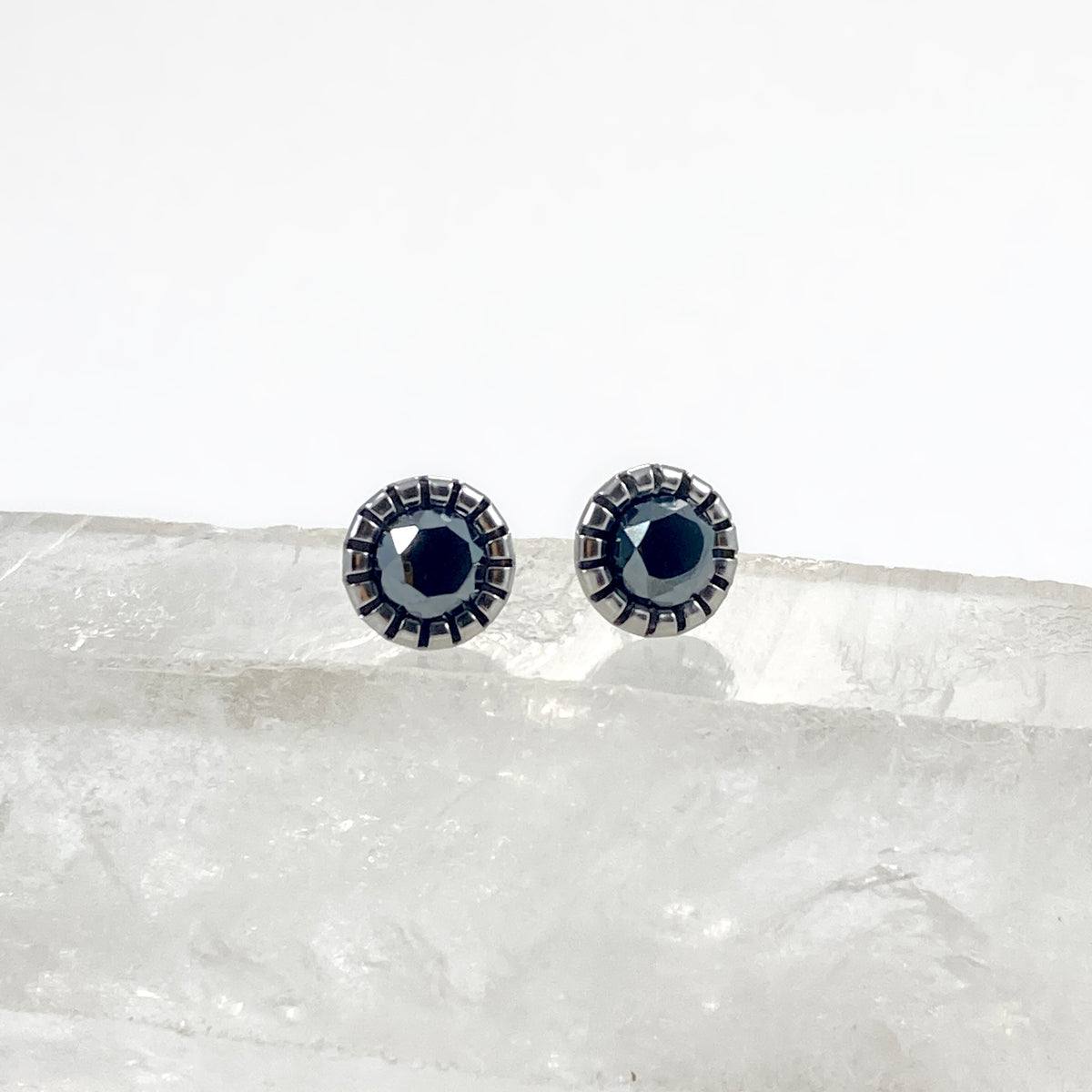 Faceted Hemalyke stud earrings front view on raw white crystal with 6mm mirror-like black gunmetal faceted stones in scalloped bezel settings, sleek black stud earrings by Blue Jeans and Pearls Saskatchewan